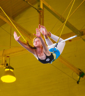 Youn person swinging on the flying trapeze | Kids Parties | Circus Center